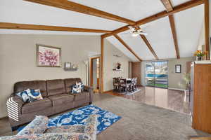 Carpeted living room with beamed ceiling and ceiling fan