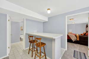Kitchen featuring a bar, light countertops, light tile patterned floors