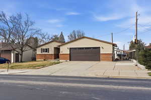 View of front facade featuring brick, siding, an attached garage, and driveway