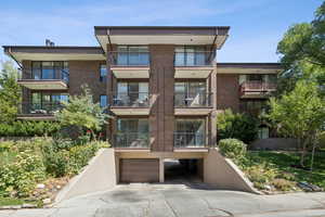 View of apartment building / complex featuring a garage and concrete driveway
