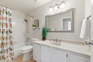 Bathroom featuring vanity, shower / bath combo, and light tile patterned floors