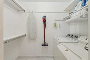 Laundry room featuring washing machine and clothes dryer and light marble finish flooring