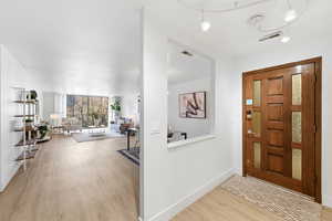 Entryway with light wood-type flooring and expansive windows