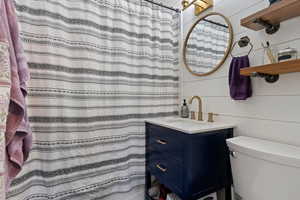Full bath with a shower with shower curtain, wood walls, and vanity
