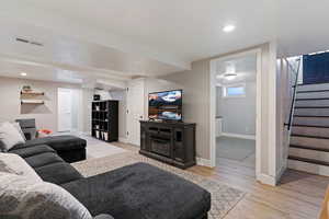 Living room featuring light wood-style floors, recessed lighting, and a glass covered fireplace