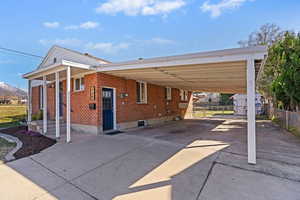 Back of property with an attached carport, driveway, and brick siding