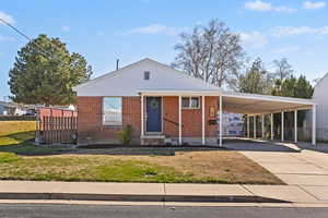 View of front of house featuring a carport, driveway, and brick siding