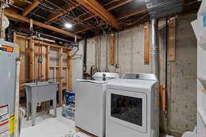Laundry area with gas water heater, independent washer and dryer, and concrete flooring