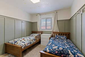 Bedroom featuring a decorative wall and a wainscoted wall