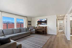 Living room featuring light wood-style floors, a mountain view, wooden walls, and recessed lighting