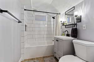 Full bath featuring vanity, shower / bath combo with shower curtain, light wood finished floors, and a textured ceiling