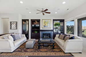 Living room with a fireplace, a ceiling fan, recessed lighting, and built in shelves
