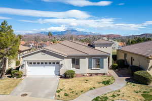 Mediterranean / spanish-style house with stucco siding, an attached garage, driveway, a mountain view, and a tiled roof