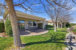 Back of house featuring stucco siding, a lawn, a patio area, and a tiled roof