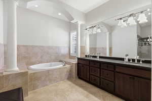Bathroom featuring double vanity, a garden tub, a shower stall, ornate columns, and recessed lighting