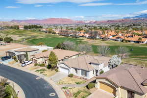 Aerial perspective of suburban area featuring a golf course and a mountainous background