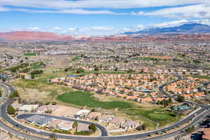 Aerial perspective of suburban area featuring a golf course and a mountainous background