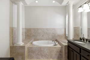 Bathroom featuring vanity, a bath, recessed lighting, and decorative columns