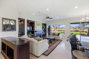 Living area with ceiling fan, a residential view, a glass covered fireplace, light tile patterned floors, and hanging lights