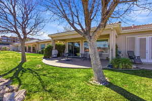 Rear view of house with a lawn, stucco siding, a patio, and a tile roof