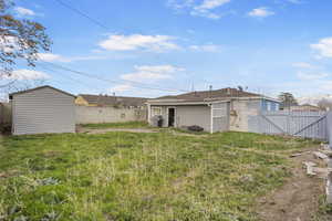 Back of house with a fenced backyard, a shed, and a gate