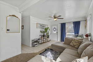 Living room with light tile patterned flooring, crown molding, and a ceiling fan