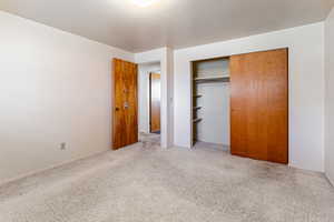 Unfurnished bedroom with a closet and light carpet