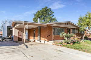 View of front facade featuring an attached carport, brick siding, and concrete driveway
