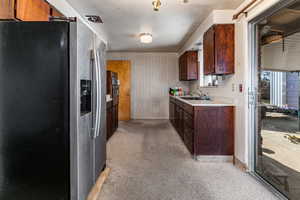 Kitchen featuring stainless steel appliances, light countertops, wallpapered walls, and dark wood finish cabinetry