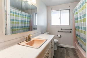 Bathroom with vanity, shower / bath combo, and dark wood-style floors