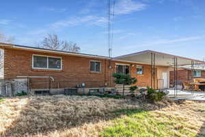 Back of house featuring a patio, a carport, and brick siding