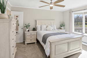 Bedroom with crown molding, light colored carpet, and ceiling fan
