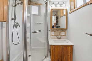 Full bath with a stall shower, vanity, and decorative backsplash