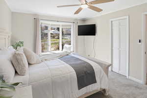 Bedroom featuring light carpet, ornamental molding, ceiling fan, and a closet