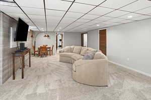 Living room with a paneled ceiling, light colored carpet, and recessed lighting