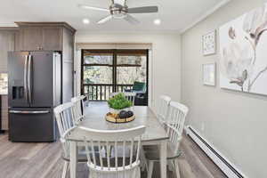 Dining space featuring a baseboard heating unit, a ceiling fan, light wood finished floors, crown molding, and recessed lighting