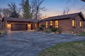 View of front of house with asphalt driveway, an attached garage, brick siding, and roof with shingles