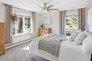 Bedroom featuring a baseboard radiator, light colored carpet, and ceiling fan