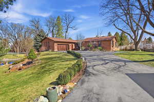 Single story home featuring driveway, brick siding, an attached garage, and a front yard
