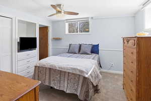 Carpeted bedroom with ceiling fan and a closet
