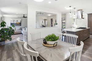 Dining space with dark wood-type flooring, ceiling fan, ornamental molding, and recessed lighting