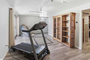 Workout room featuring light wood-style floors and track lighting