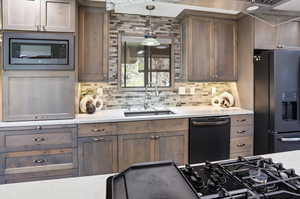 Kitchen featuring black appliances, backsplash, light stone countertops, and pendant lighting