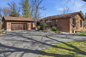 Ranch-style house featuring brick siding, driveway, a garage, and a shingled roof