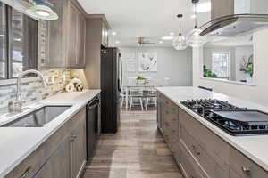 Two tone kitchen featuring extractor fan, black appliances, two tone cabinetry, decorative light fixtures, and arched walkways