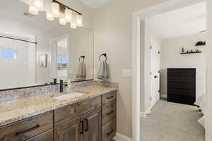Full bathroom featuring vanity, light carpet, and a tile shower