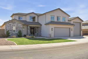 Traditional-style home featuring concrete driveway, stucco siding, an attached garage, and stone siding