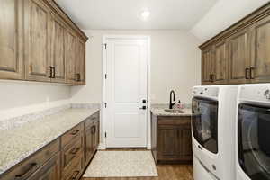 Laundry area featuring cabinet space, washing machine and dryer, light wood-style flooring, and lofted ceiling