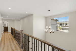 Hall featuring light wood-type flooring, an upstairs landing, hanging lights, and a mountain view