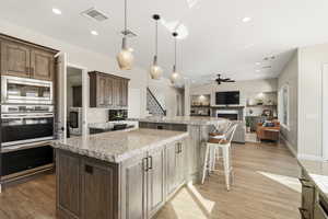 Kitchen featuring light stone counters, a kitchen breakfast bar, stainless steel appliances, and a center island